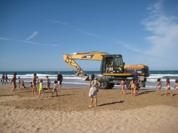 Xiquets jugant a la platja amb una excavadora al costat